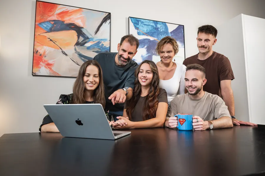 The Clientology team gathered around a laptop, pointing at a customer journey